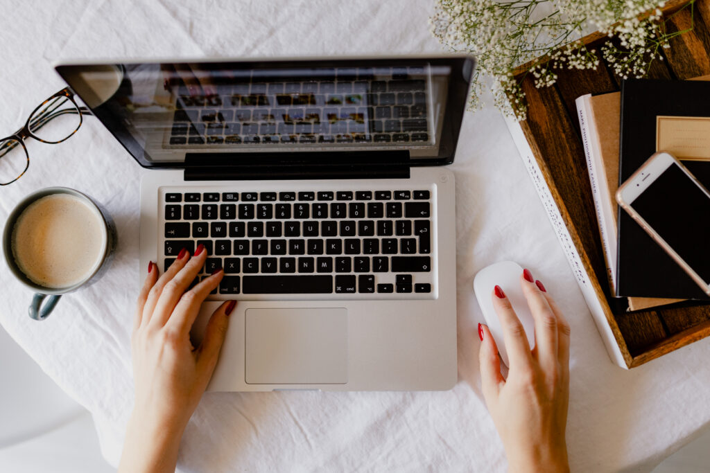 Woman working on a laptop with coffee and phone nearby, representing a productive workspace for SEO consulting and marketing.