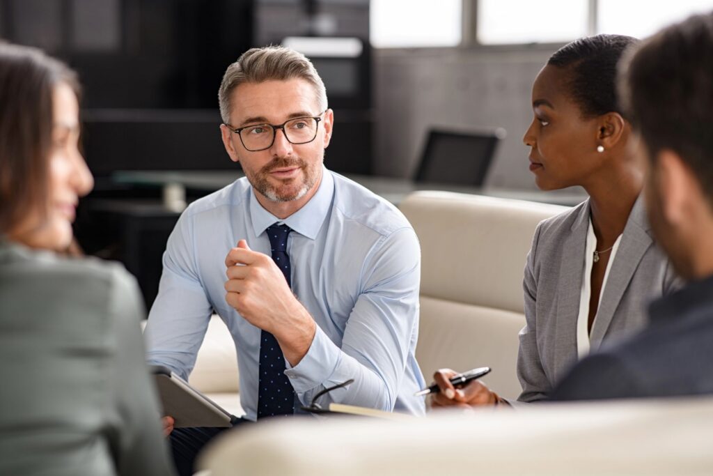 A group of professionals in business attire sitting together in an office for a meeting.